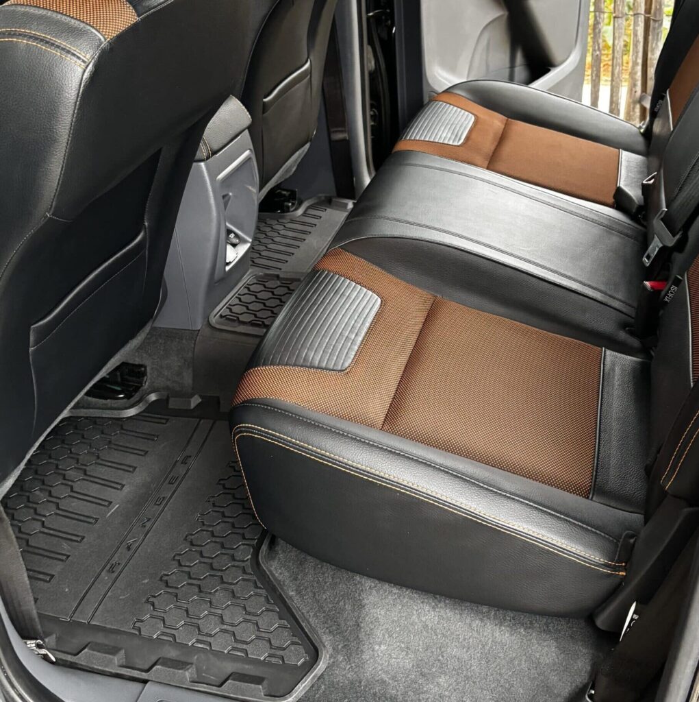 Intérieur arrière Ford Ranger: sièges bicolores cuir noir et tissu brun-orangé, surpiqûres, et tapis de sol RANGER en caoutchouc.