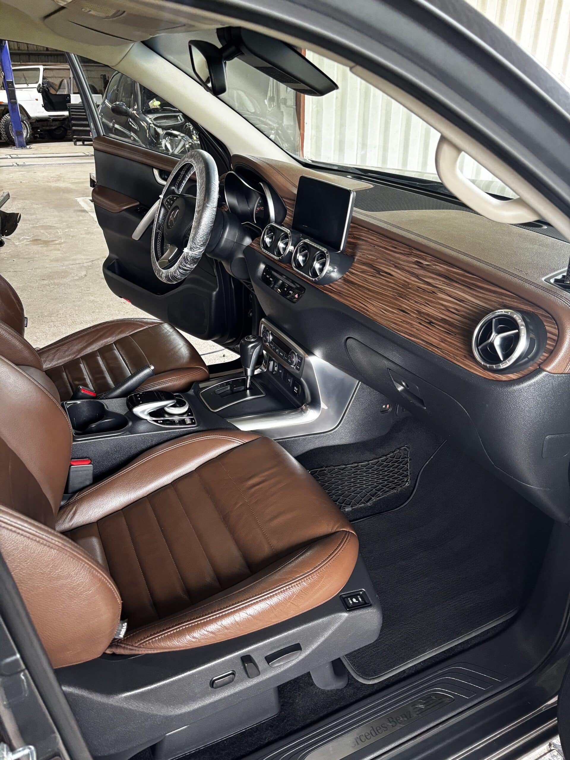Intérieur Mercedes-Benz avec sièges en cuir marron, tableau de bord en bois et console centrale de luxe.