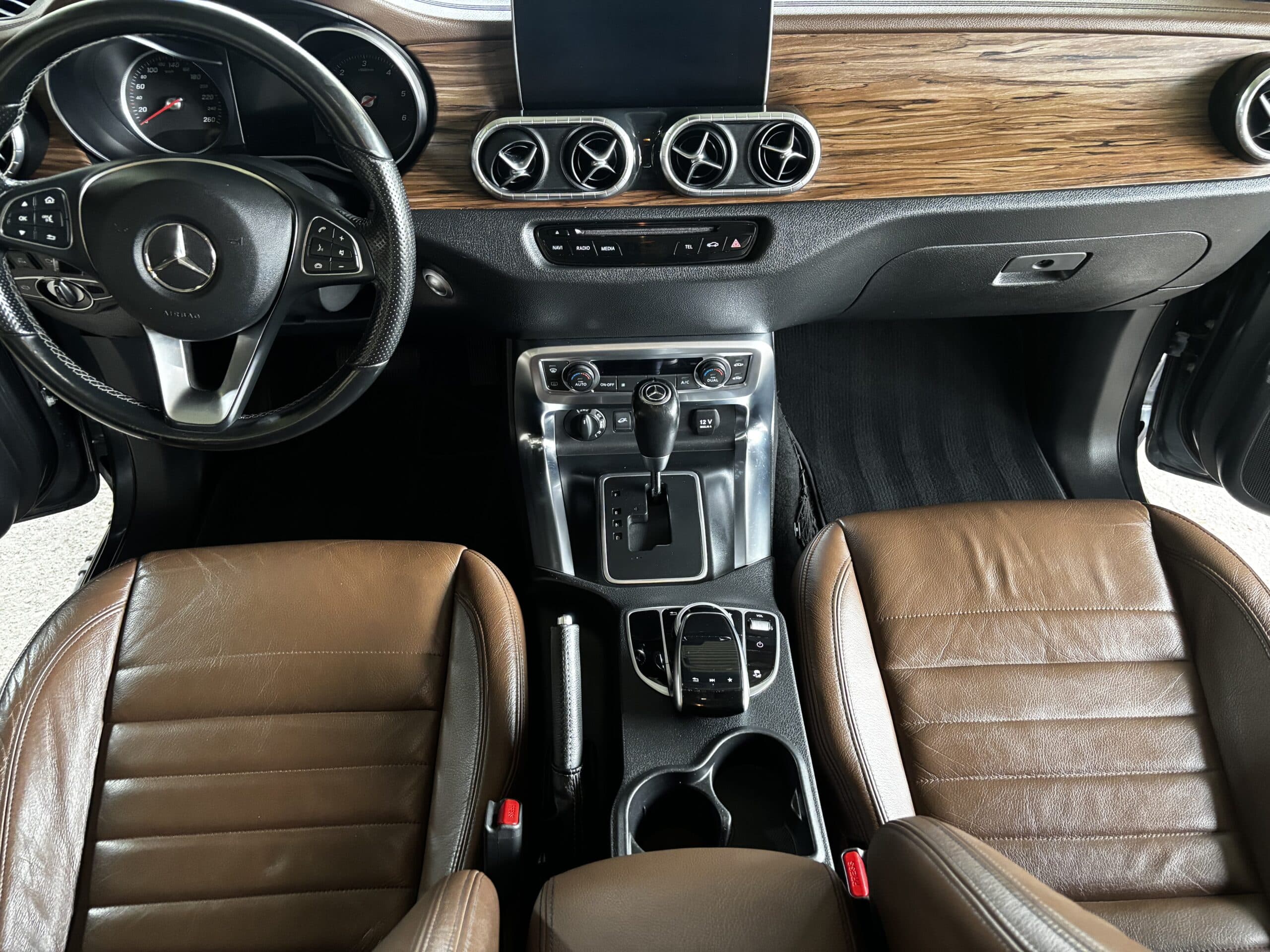 Intérieur luxueux Mercedes-Benz avec sièges cuir marron, finitions bois et console centrale moderne.