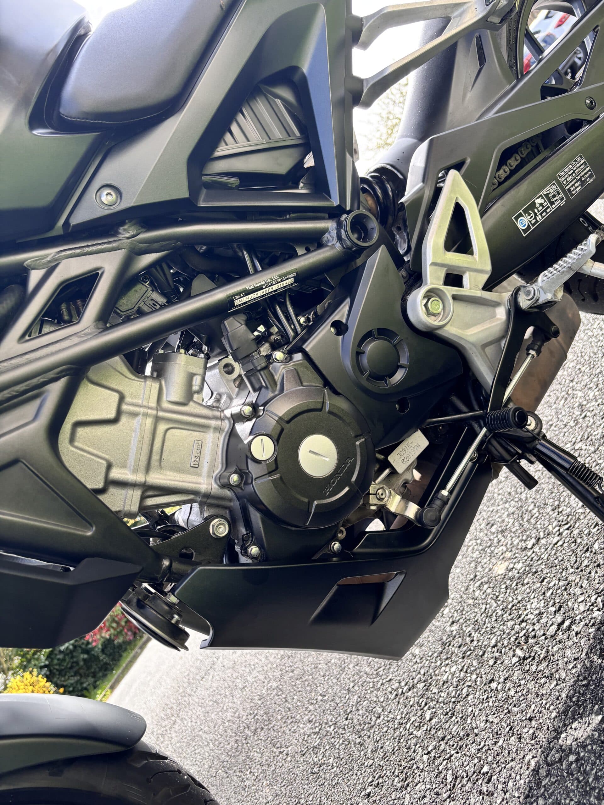 Moteur Honda 124 cm³, châssis noir et détails mécaniques d'une moto de route moderne.