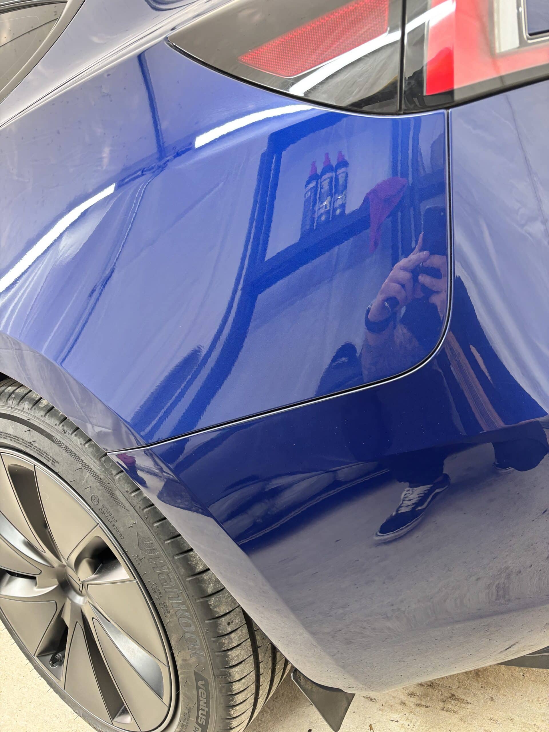 Tesla Model Y bleu outremer avec jante noire et pneu Hankook Ventus. Carrosserie brillante et aile arrière.